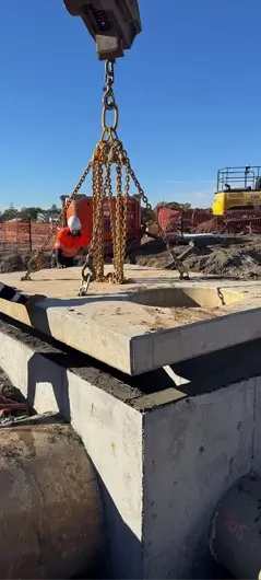 Barrow Construction civil FRP worker guiding crane-lifted precast concrete pit lid installation on a Queensland infrastructure project.